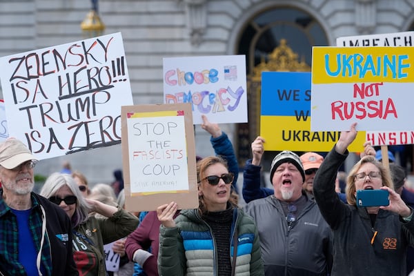 People hold up signs as they protest the Trump administration outside City Hall, Tuesday, March 4, 2025, in San Francisco. (AP Photo/Godofredo A. Vásquez)