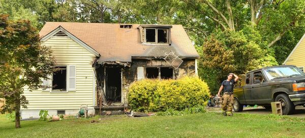 DeKalb firefighter Juan Albarracin wipes his brow as firefighters clean up after a fatal blaze on Medlock Road.