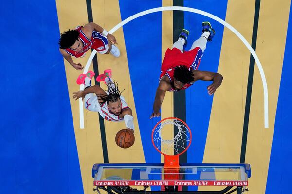 New York Knicks' Jalen Brunson, bottom left, goes up for a shot between Philadelphia 76ers' Joel Embiid, right, and Jared McCain during the second half of an Emirates NBA Cup basketball game, Tuesday, Nov. 12, 2024, in Philadelphia. (AP Photo/Matt Slocum)