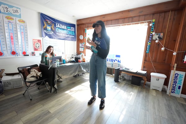 Democratic state Rep. Jaime Churches looks over her phone before going door to door to campaign, Friday, Oct. 11, 2024, in Trenton, Mich. (AP Photo/Carlos Osorio)