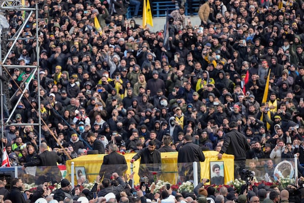 A trailer carrying the coffins containing the bodies of Hezbollah's former leader Hassan Nasrallah and his cousin and successor Hashem Safieddine drives through the crowd at the beginning of a funeral procession in the Sports City Stadium in Beirut, Lebanon, Sunday, Feb. 23, 2025. (AP Photo/Hussein Malla)