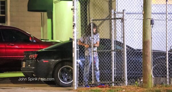 A studio employee works to close the gate where police believe the shooters forced their way into the parking lot. JOHN SPINK / JSPINK@AJC.COM