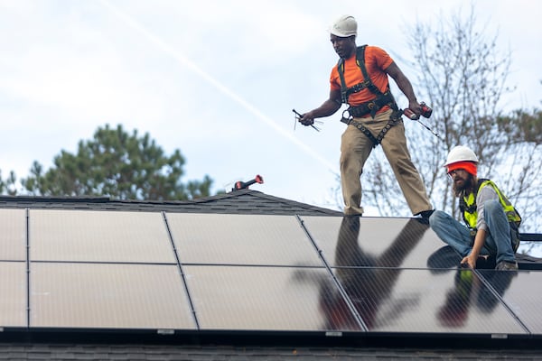 Joe McClain, right, and Mike Harris, left, installers for Creative Solar USA, install solar panels on a home in Ball Ground, Georgia on December 17th, 2021.