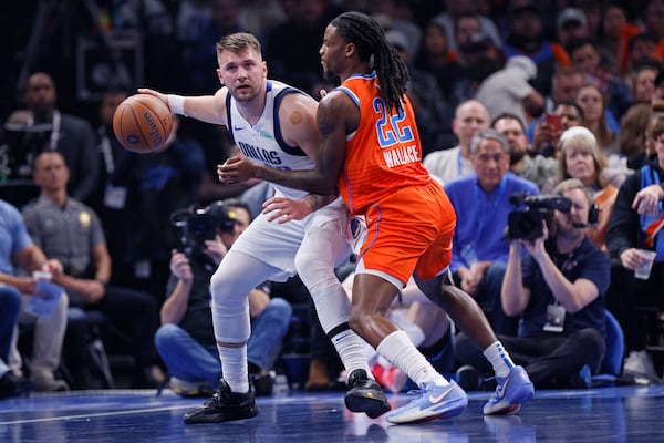 Dallas Mavericks guard Luka Doncic, left, handles the ball as Oklahoma City Thunder guard Cason Wallace (22) defends during the first half of an Emirates NBA Cup basketball game, Tuesday, Dec. 3, 2024, in Oklahoma City. (AP Photo/Nate Billings)