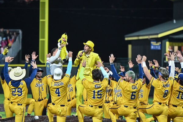 Savannah Bananas team owner Jesse Cole, sporting his trademark yellow suit, leads the pregame ritual of presenting the Banana Baby to the theme of "The Lion King"  on Friday at Grayson Stadium in Savannah. Sarah Peacock for the AJC