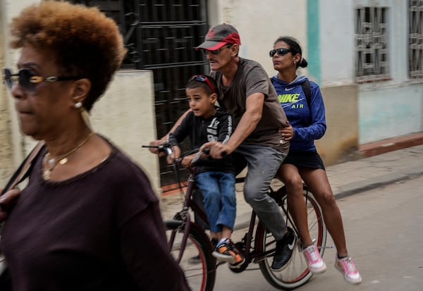 A trio rides a bicycle during a blackout in Havana, Cuba, Wednesday, Dec. 4, 2024. (AP Photo/Ramon Espinosa)