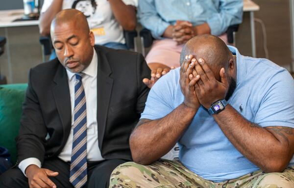 The family and attorneys supporting Nygil Cullins meet for a press conference after the body camera footage was released by Atlanta Police Department showing the 2022 shooting death of the 20-year-old at a  Fogo de Chao in Buckhead.  Family attorney Leif Howard, left, comforts Nygil’s father Quinten Cullins on Tuesday, June 11, 2024.  They are asking for the unedited version of the footage to be released and transparency regarding the death.  (Jenni Girtman for The Atlanta Journal Constitution)