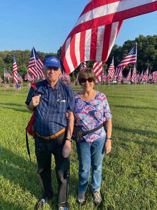 Eric and Nancy Lucas pose for a photo amid the nearly 3,000 flags at Kennesaw Mountain National Battlefield Park to honor those who died on Sept. 11, 2001 an entire two decades ago. (Ben Brasch/The AJC)