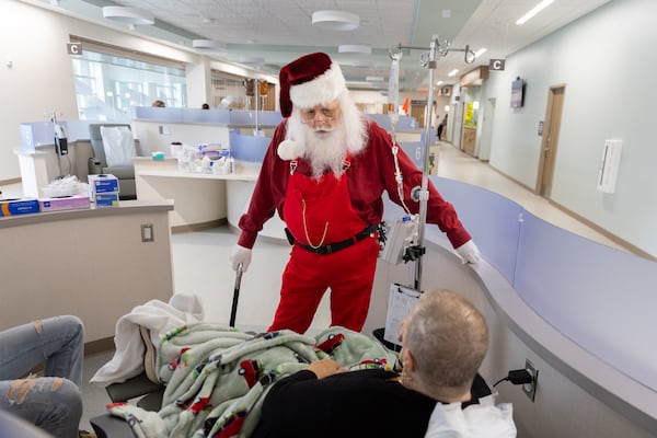 Former patient Jonathan Byrd, who is a favorite local Santa Claus, chats with patient Angela Whitehead at University Cancer & Blood Center in Athens on Wednesday, Dec. 18, 2024. Byrd’s cancer is in remission. (Arvin Temkar/AJC)