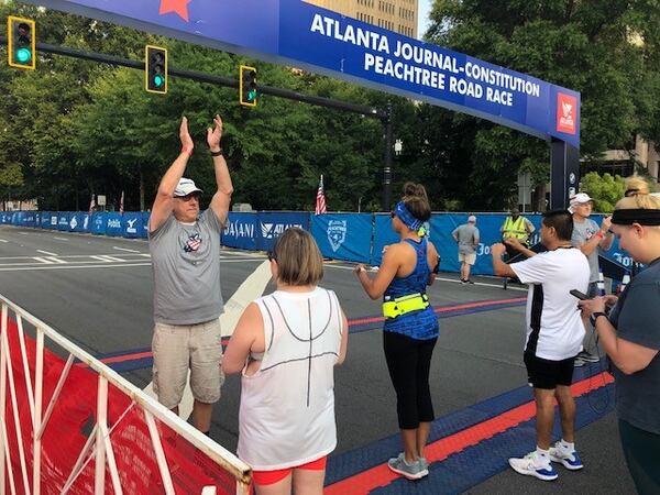 AJC Peachtree Road Race volunteer Richard Smith organizes runners and walkers at the start line of the race July 3, 2021. (AJC photo by Ken Sugiura)