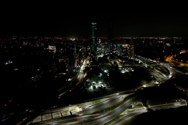 Cars zip past dark buildings during a power outage in Santiago, Chile, Tuesday, Feb. 25, 2025. (AP Photo/Matias Basualdo)