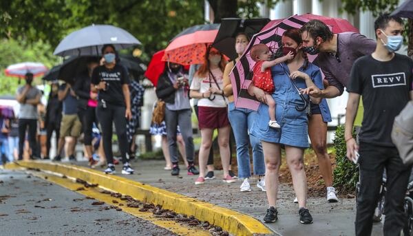 Amanda McElveen holds 1-year old Luna (left) as Dad, Justin McElveen (right) interacts while they and other voters lined up in the rain on Friday, June 6, 2020 at Garden Hills Elementary School located at 285 Sheridan Drive NE, in Atlanta. Some waited up to three hours to vote. JOHN SPINK/JSPINK@AJC.COM