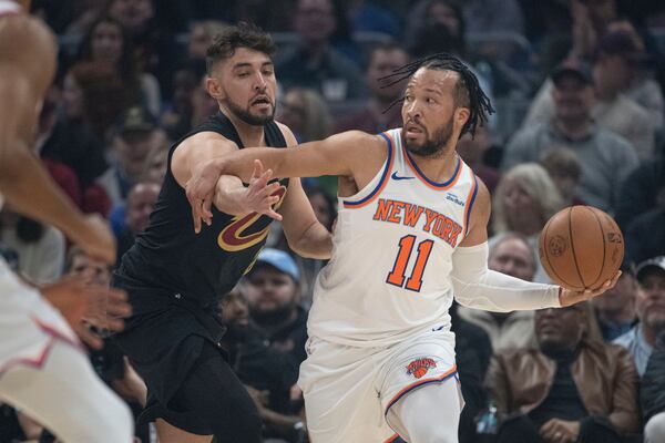 New York Knicks' Jalen Brunson (11) looks to pass as Cleveland Cavaliers' Ty Jerome, left, defends during the first half of an NBA basketball game in Cleveland, Friday, Feb. 21, 2025. (AP Photo/Phil Long)