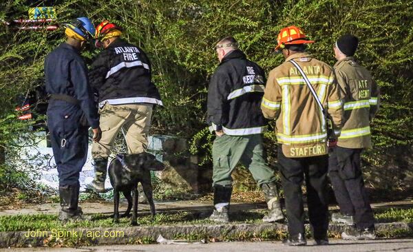 Authorities use a police dog in their investigation into a deadly fire in northwest Atlanta. JOHN SPINK / JSPINK@AJC.COM