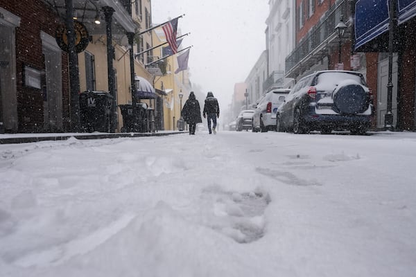 People walk in the French Quarter as snow falls in New Orleans, Tuesday, Jan. 21, 2025. (AP Photo/Gerald Herbert)