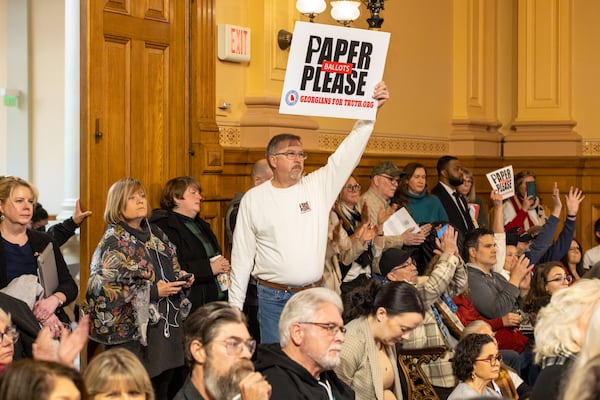 Paper ballot supporter Sam Carnline of Grady County holds a sign at a State Election Board meeting in December at the Georgia Capitol in Atlanta. (Arvin Temkar/AJC)