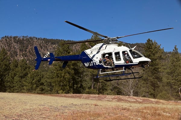 This Jan. 30, 2025, image provided by the Arizona Game and Fish Department shows a helicopter transporting an endangered Mexican gray wolf that was captured as part of an annual population survey near Alpine, Arizona. (Arizona Game and Fish Department via AP)