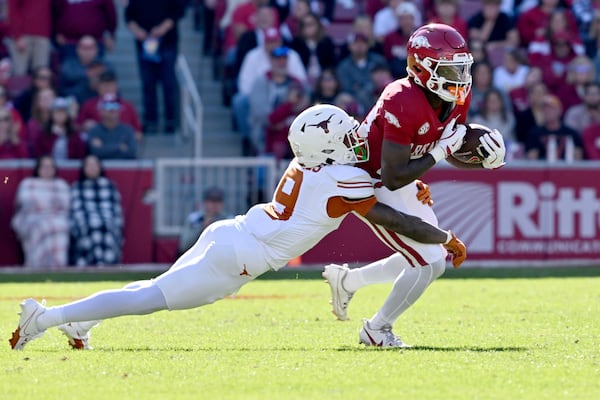 Arkansas running back Rodney Hill (20) is tackled by Texas defensive back Gavin Holmes (9) during the first half of an NCAA college football game Saturday, Nov. 16, 2024, in Fayetteville, Ark. (AP Photo/Michael Woods)