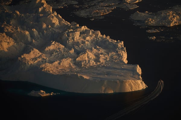 A boat sails past a large iceberg in Ilulissat, Greenland, Wednesday Feb. 18, 2025. (AP Photo/Emilio Morenatti)