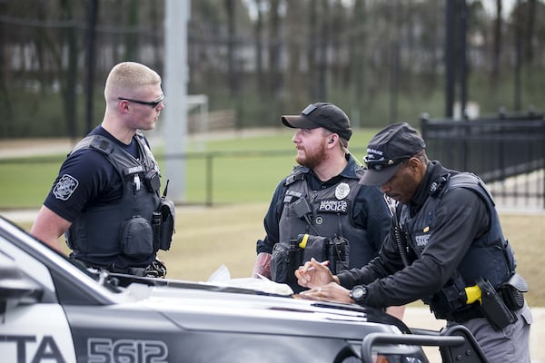 01/15/2019 — Marietta, Georgia — Marietta Police Officers Aaron Johnson (left) and Ryan Brown (center) talk as Marietta Prisoner Transport Officer Gary Hicks (right) fills out paperwork following an arrest near the Franklin Gateway Sports Complex in Marietta, Wednesday, January 15, 2020. (ALYSSA POINTER/ALYSSA.POINTER@AJC.COM)