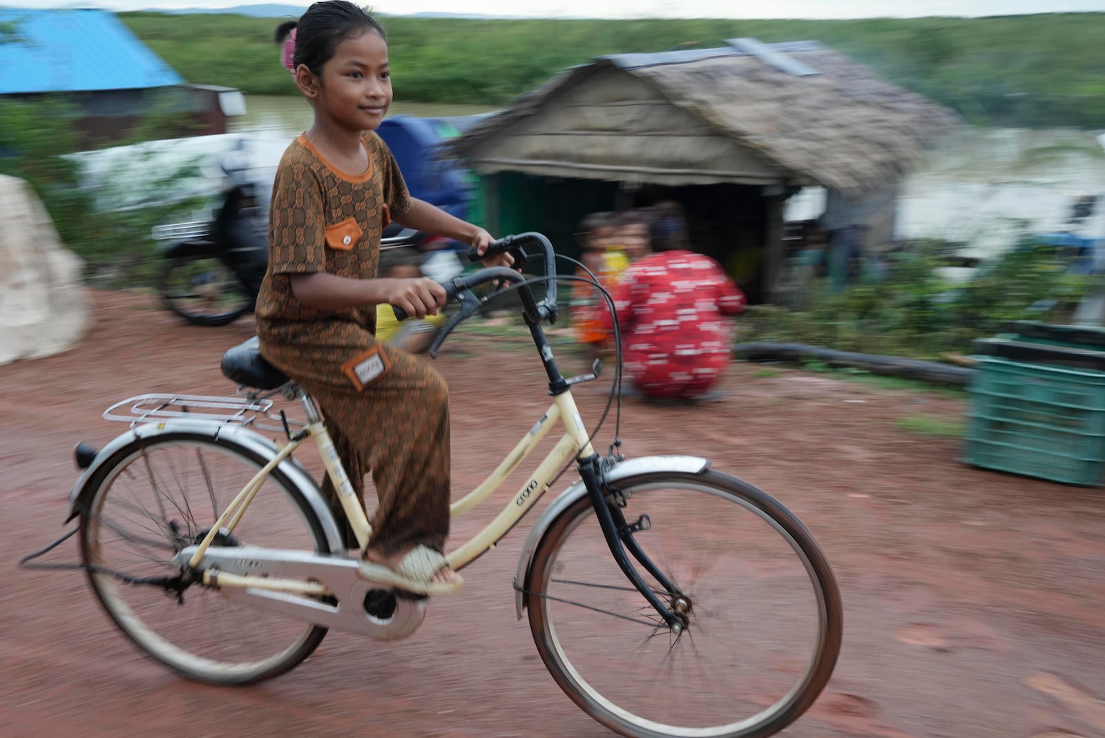 A girl rides a bicycle at a floating village, by the Tonle Sap in Kampong Chhnang province, Cambodia, Thursday, Aug. 1, 2024, (AP Photo/Heng Sinith)