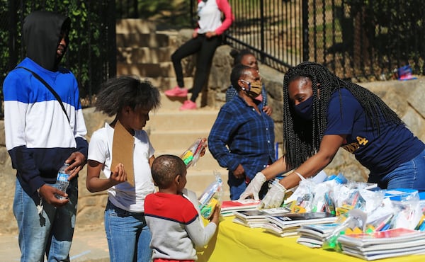 Jocelyn Watkins (far right) hands out school supplies to community members at the Grab and Go free food and groceries event on Friday, April 17, 2020, at Allen Hills Apartments in Atlanta. The event to help families during the COVID-19 pandemic was led by the Fulton County district attorney’s office. (Christina Matacotta, for The Atlanta Journal-Constitution)