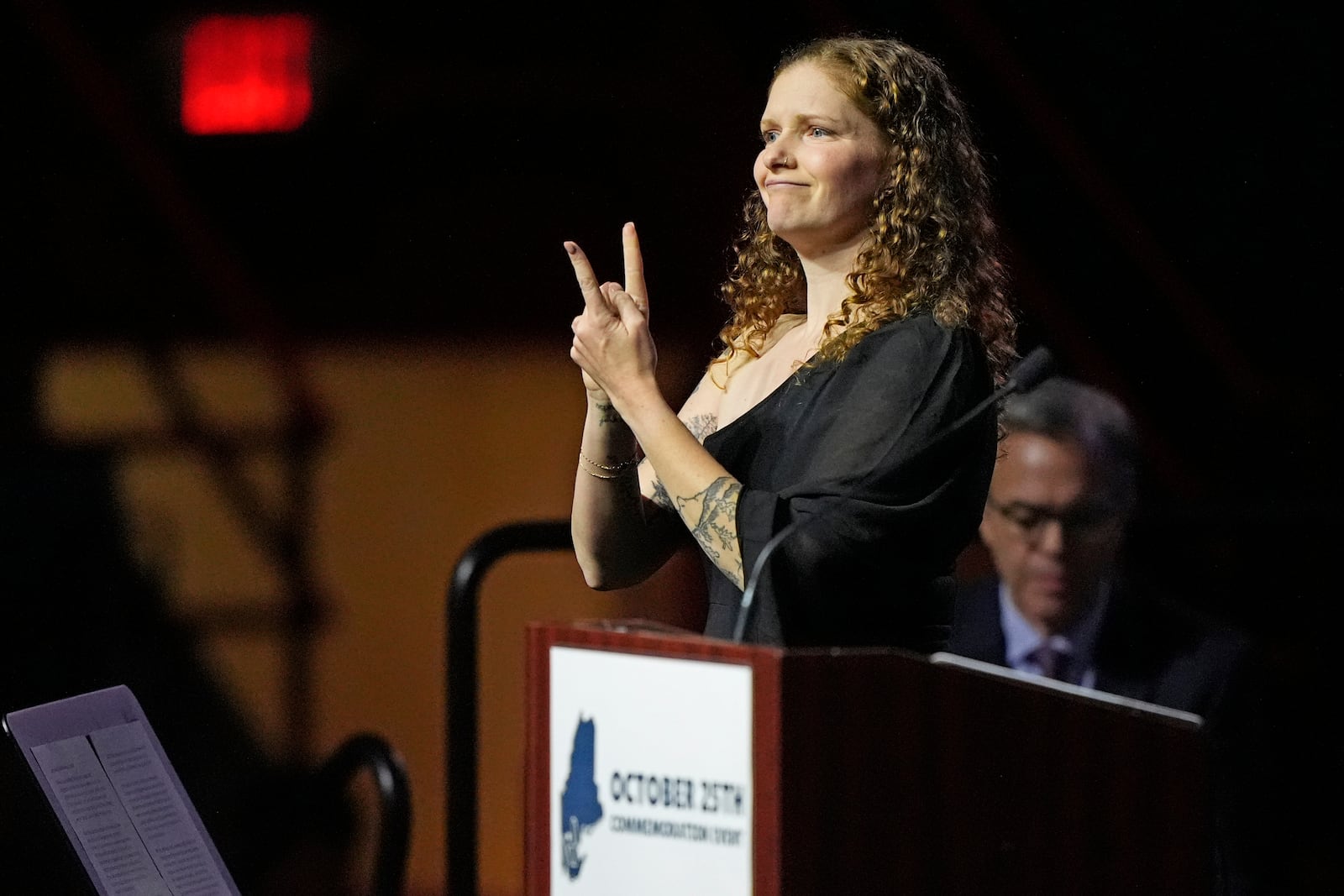 Elizabeth Seal, the wife of Joshua Seal, one of the four deaf victims in the Lewiston, Maine mass shooting, uses sign language as she addresses a commemoration event to mark the one year anniversary of the mass shooting in Lewiston, Maine, Friday, Oct. 25, 2024. (AP Photo/Robert F. Bukaty)