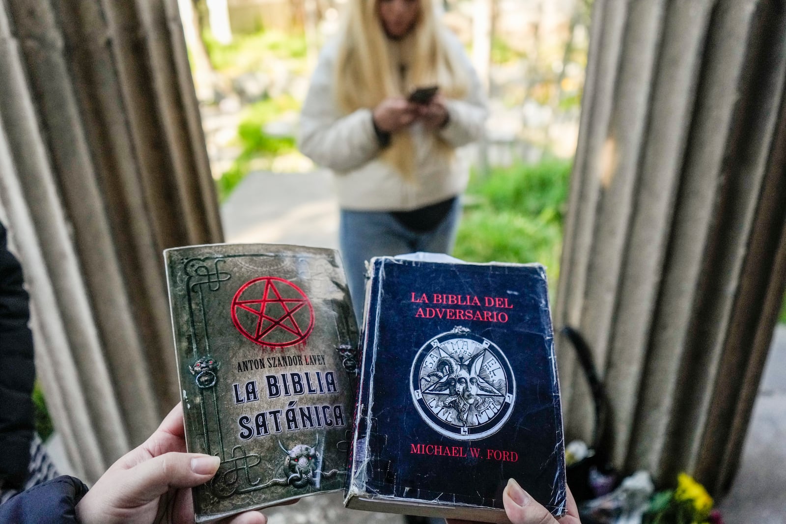 A woman holds copies of The Satanic Bible by Church of Satan founder Anton Szandor LaVey and The Bible of the Adversary by Michael Ford, before the start of a ceremony at the General Cemetery in Santiago, Saturday, Sept. 14, 2024. (AP Photo/Esteban Felix)