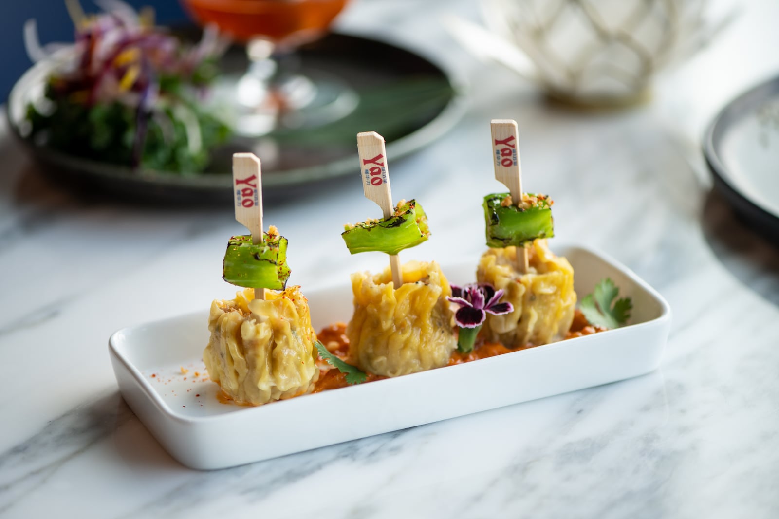 Yao Dumplings with chicken, shrimp, pork, napa cabbage, green onions, cilantro, charred shishito peppers, and sambal sauce. (Mia Yakel for The Atlanta Journal-Constitution)