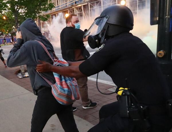 A police officer in riot gear grabs a protester to make an arrest after curfew on Sunday, May 31, 2020 — the third day of protests in Atlanta over the recent deaths of unarmed black people in Minneapolis; Brunswick, Georgia; and Louisville, Kentucky, at the hands of police officers or civilians acting as law enforcers. (Curtis Compton / ccompton@ajc.com)