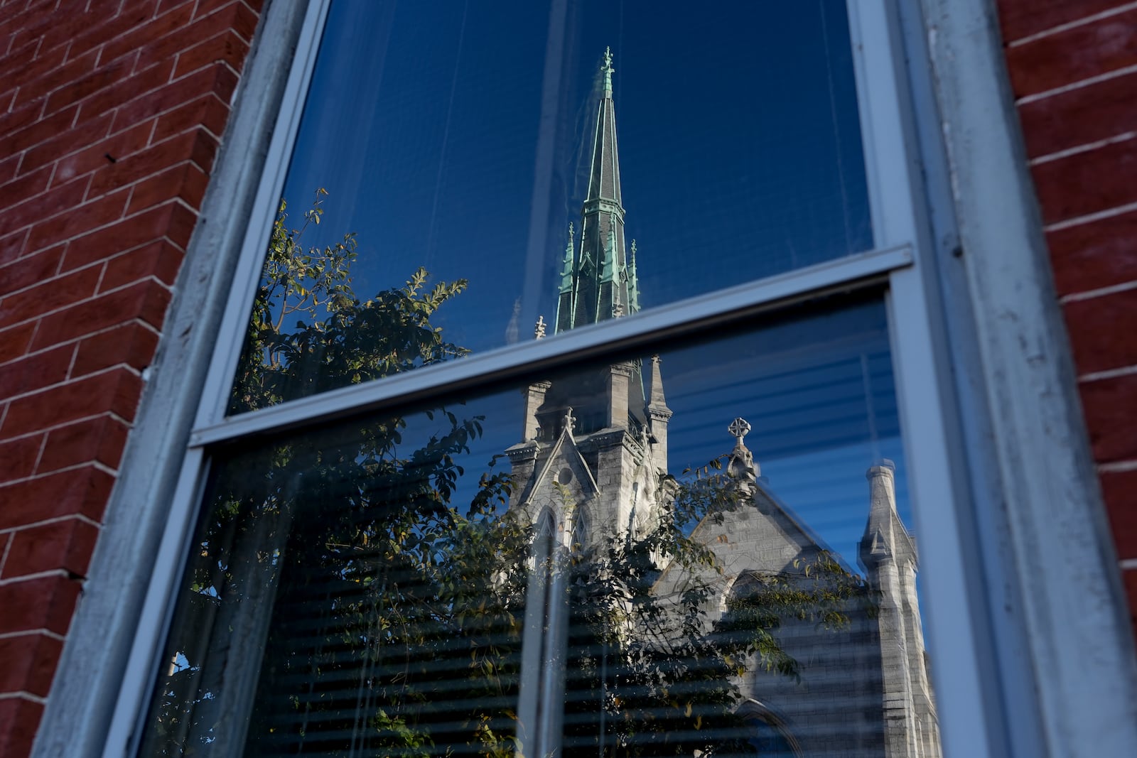 Grace United Methodist Church is reflected on the window of a building across from the church in Harrisburg, Pa., on Sunday, Oct. 27, 2024. (AP Photo/Luis Andres Henao)