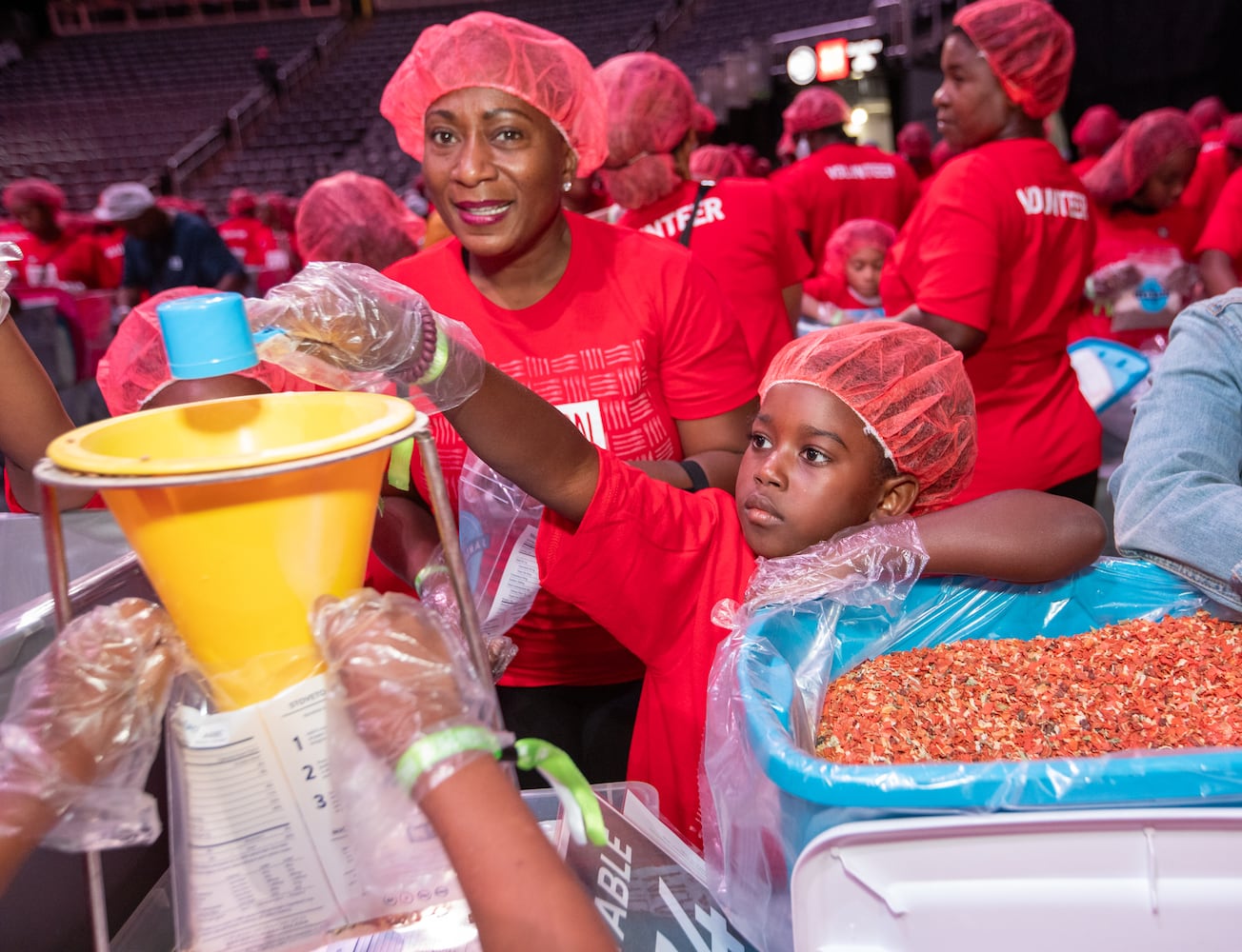 Cherisse  Chisolm (left) and 8-year-old Tatum Dunn mix ingredients for red lentil jambalaya kits.  (Jenni Girtman for The Atlanta Journal-Constitution)