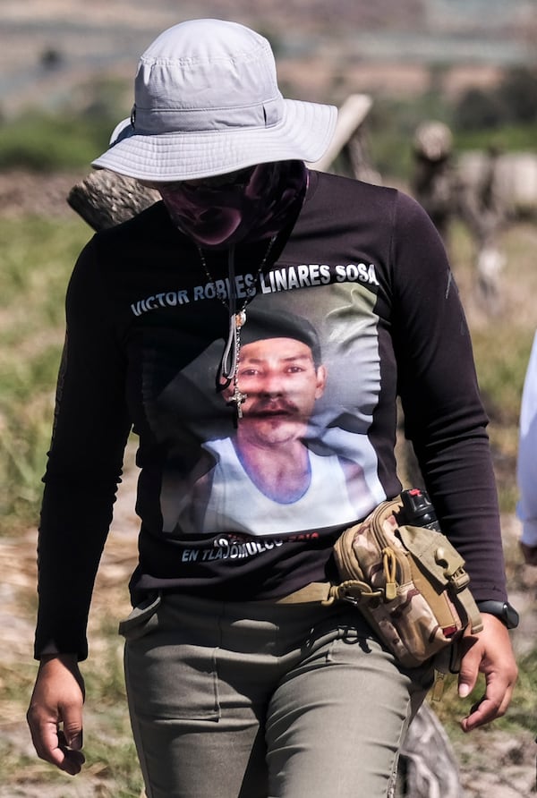 A woman wears a T-shirt with the image of a missing relative outside Izaguirre Ranch where she came to see if any of the skeletal remains discovered belong to her missing family member in Teuchitlan, Jalisco state, Mexico, Thursday, March 13, 2025. (AP Photo/Alejandra Leyva)