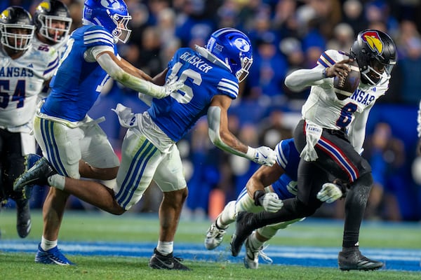 Kansas quarterback Jalon Daniels (6) is chased down by BYU linebacker Isaiah Glasker (16) and two other defenders in an NCAA college football game Saturday, Nov. 16, 2024, in Provo. (AP Photo/Rick Egan)