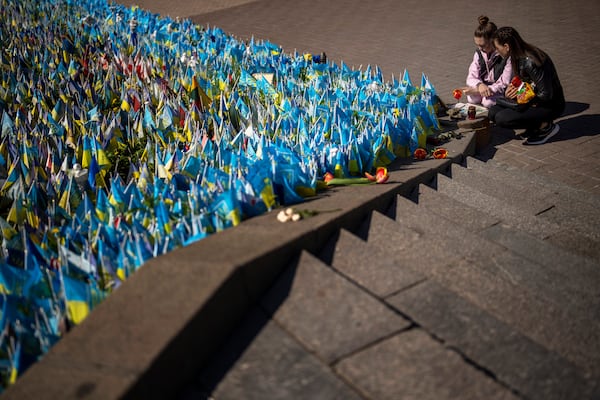 Two woman look at Ukrainian flags placed in memory of civilians and soldiers killed during the war at the Independence Square in central Kyiv, Saturday, April 20, 2024. (AP Photo/Francisco Seco)