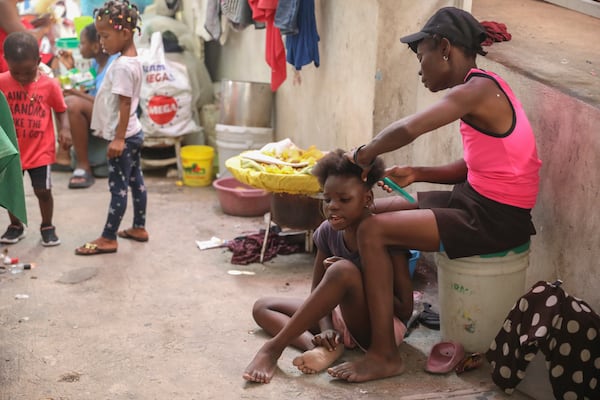 A woman combs the hair of a girl inside a shelter for people who have fled their home to escape gang violence in Port-au-Prince, Haiti, Friday, Feb. 28, 2025.(AP Photo/Odelyn Joseph)