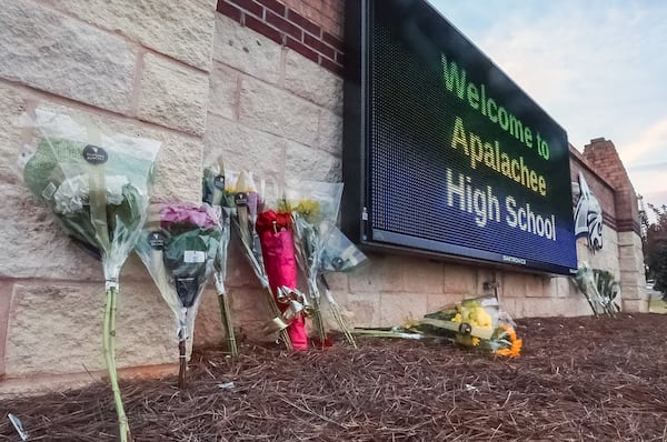 Flowers are placed at the foot of the welcome sign to Apalachee High School, where four people were killed and nine others were injured during a mass shooting. Colt Gray, a 14-year-old student, faces four murder charges in the shooting, and his father has been charged with second-degree murder. Warrants allege that he gave his son access to the semiautomatic rifle used in the shooting even though he knew the teen was a danger to himself and others. (John Spink/The Atlanta Journal-Constitution/TNS)