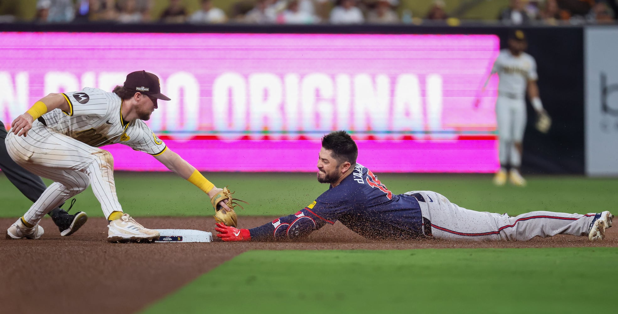 Atlanta Braves’ Travis d'Arnaud (16) slides safely into second base on a double as San Diego Padres’ Manny Machado (13) applies a late tag during the fourth inning of National League Division Series Wild Card Game One at Petco Park in San Diego on Tuesday, Oct. 1, 2024.   (Jason Getz / Jason.Getz@ajc.com)