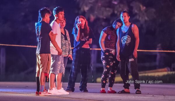 A family stands outside their Covington Highway home Thursday morning after they were forced to evacuate because of a fire. A 42-year-old man did not make it out. JOHN SPINK / JSPINK@AJC.COM