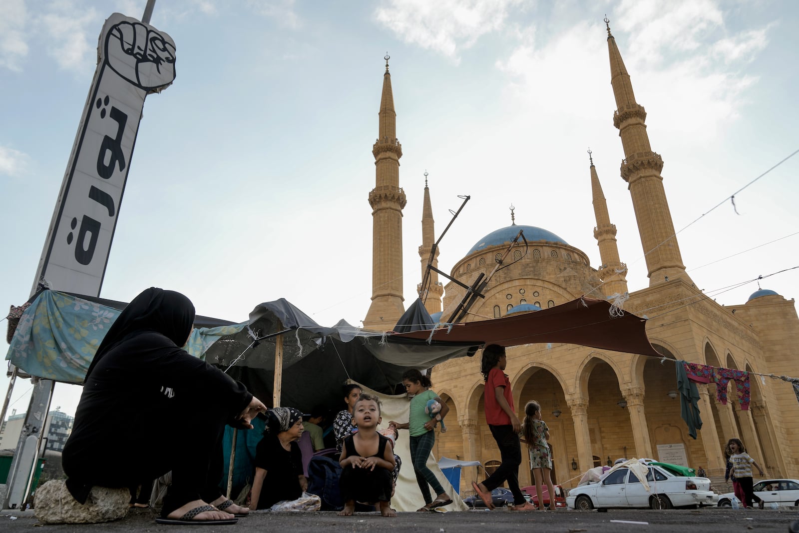 Families fleeing the Israeli airstrikes in the south, sit in front of the Mohammad al-Amin Mosque in downtown Beirut, Lebanon, Monday, Oct. 14, 2024. (AP Photo/Bilal Hussein)