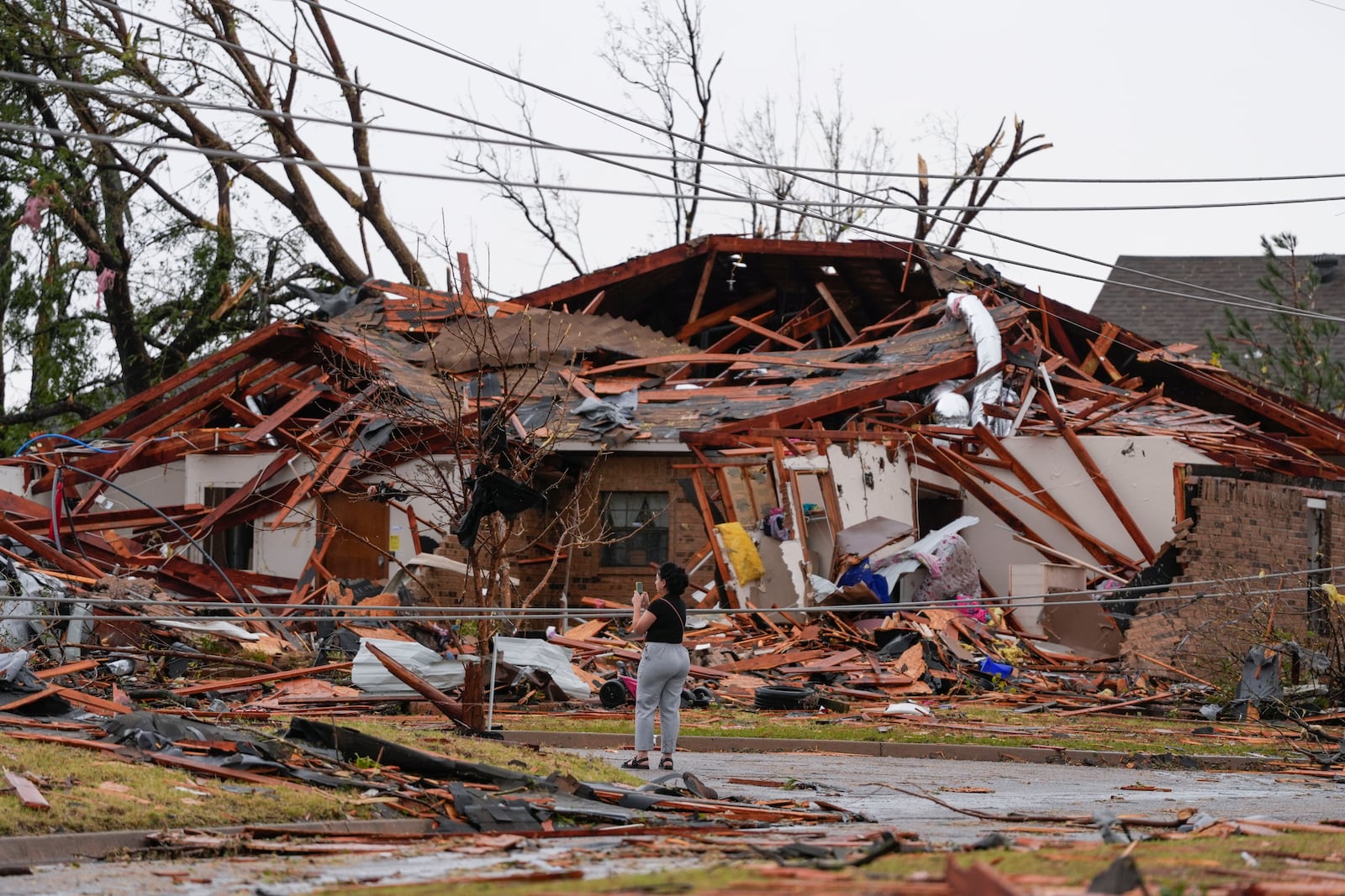 A women looks at damage to a home near SE 84 after a tornado hit the area in Oklahoma City, Sunday, Nov. 3, 2024. (Bryan Terry/The Oklahoman via AP)