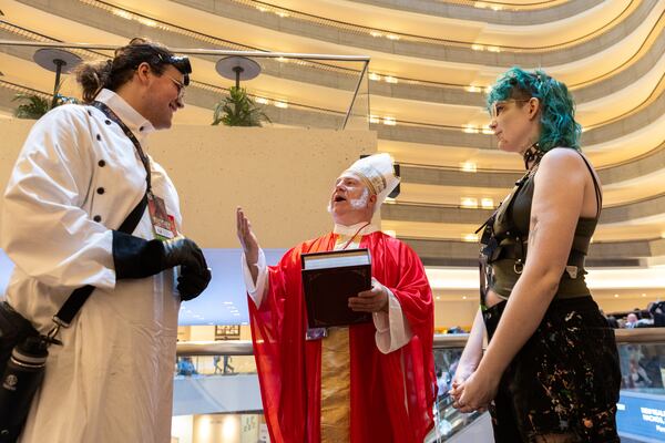 Bob Heil, cosplaying as the clergyman from the Princess Bride, performs a fake marriage ceremony for Seren Dickson and Skai Brown, cosplaying as Dr. Frankenstein and his monster, during Dragon Con in downtown Atlanta on Friday, August 30, 2024. (Arvin Temkar / AJC)