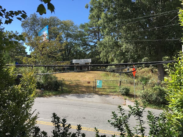 The view from an elevated Walgreens parking lot directly across the street shows an old building with a Harold E. Bailey Landscape Company sign and many trees behind a fence. Harold E. Bailey Family Trusts owns the property.