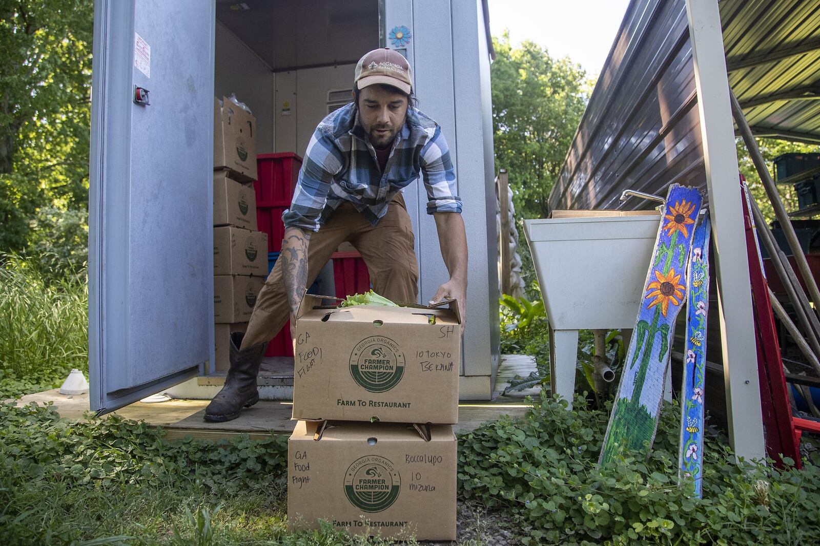 Levity Farms co-owner Zach Richards stacks prepared produce orders that are ready to be delivered from their farm in Alpharetta. The pandemic forced them to temporarily shift their business from providing 75% to 80% of their produce to local chefs to a more consumer focused home delivery model. ALYSSA POINTER / ALYSSA.POINTER@AJC.COM