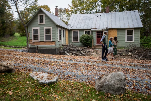 John, left, Jenny and Lila, right, Mackenzie walk around their flood-damaged property in Peachman, Vt. on Sept. 23, 2024. (AP Photo/Dmitri Beliakov)