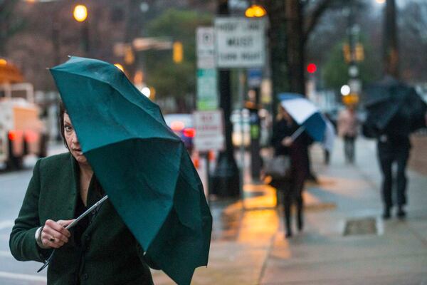 A woman peeks from under her umbrella as she walks along Ponce de Leon Avenue on Tuesday morning.  ALYSSA POINTER / ALYSSA.POINTER@AJC.COM