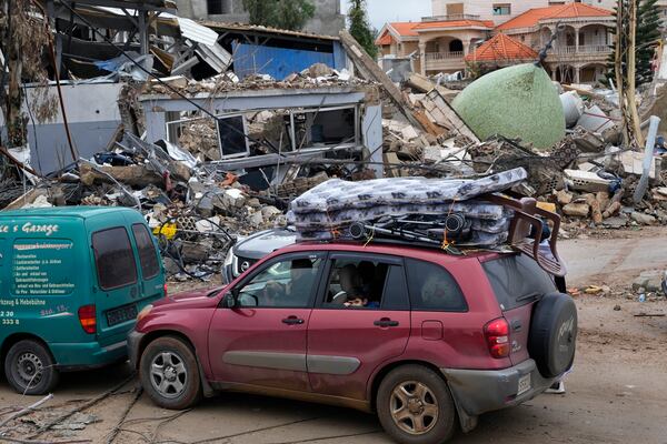 Displaced residents returning to their village, sit in their car with belonging as they pass in front of a destroyed mosque, in the town of Bint Jbeil, southern Lebanon, following a ceasefire between Israel and Hezbollah that went into effect on Wednesday, Nov. 27, 2024. (AP Photo/Hussein Malla)