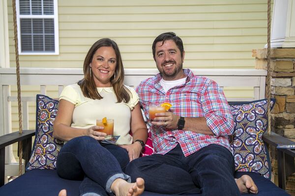 Heather and Kevin Freaney have been creating cocktails on an almost nightly basis since the COVID-19 pandemic has affected their lives. They are holding a Malibu Sunset cocktail. (ALYSSA POINTER / ALYSSA.POINTER@AJC.COM)