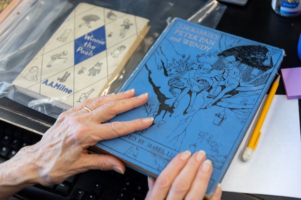 Atlanta Vintage Books owner Jan Bolga reviews a copy of "Peter Pan and Wendy" at the bookstore in Atlanta. (Arvin Temkar / AJC)