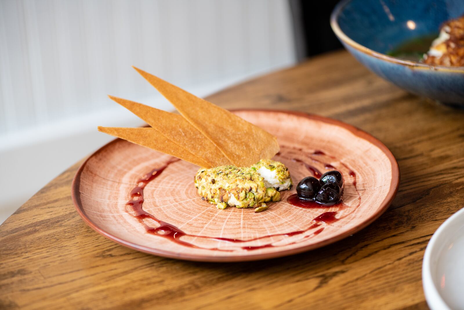 A-street Baked Goat Cheese with a pistachio crust, cherry syrup, and crispy feuilles. (Mia Yakel for The Atlanta Journal-Constitution)